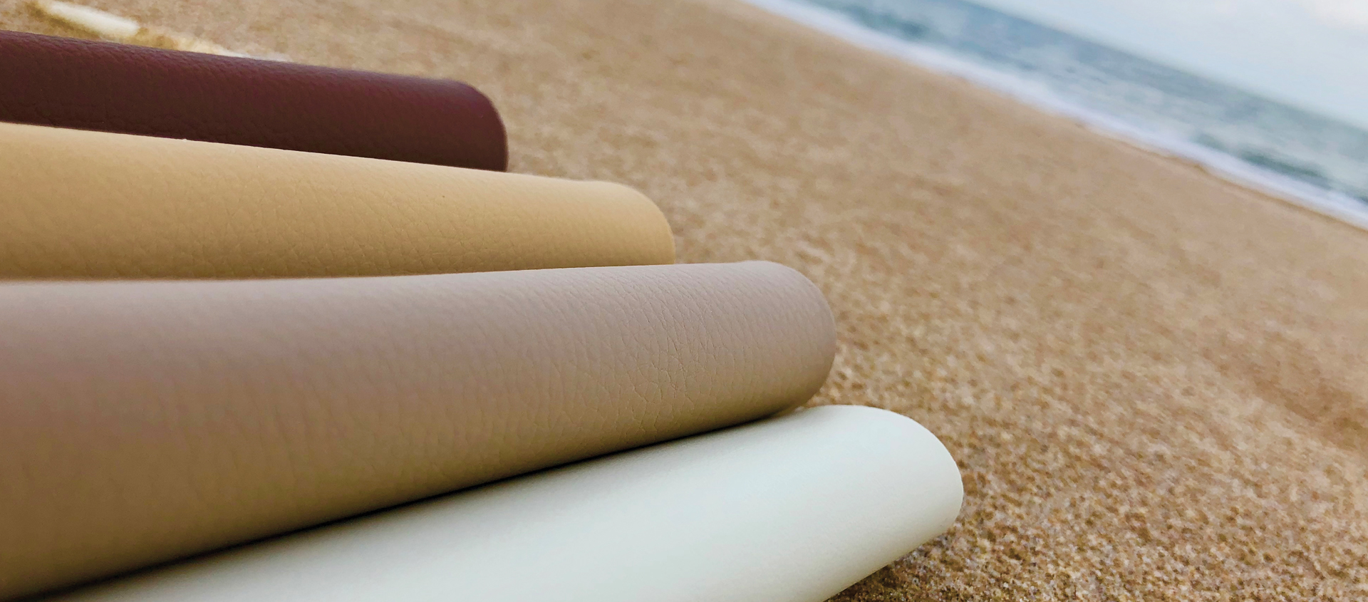 An image of rolls of Cortina Silicone Fabrics are on a sandy beach as a link to a page about silicone fabrics.