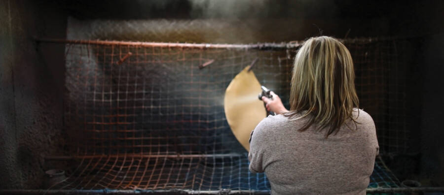 A woman hand sprays a test sample of leather for a perfect match. The image is a link to a page that is a glossary of leather terms.