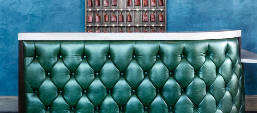 A tufted leather desk front in bright emerald green Cortina leather. The link leads to learning about Cortina's Universal High-Tech Cleaning Wipes.