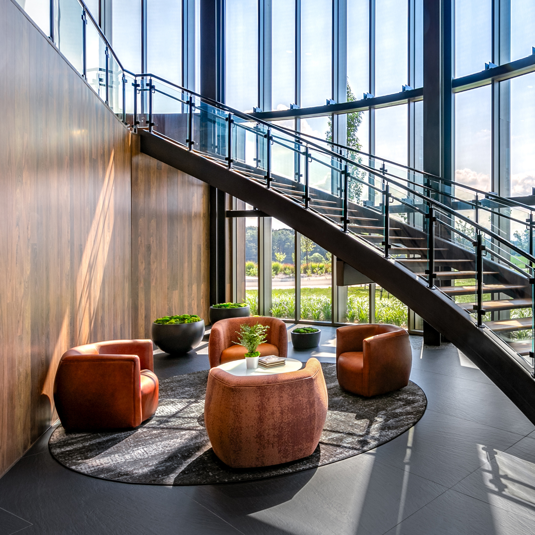 High ceiling lobby with curved staircase over a lush seating are with Cortina Leathers