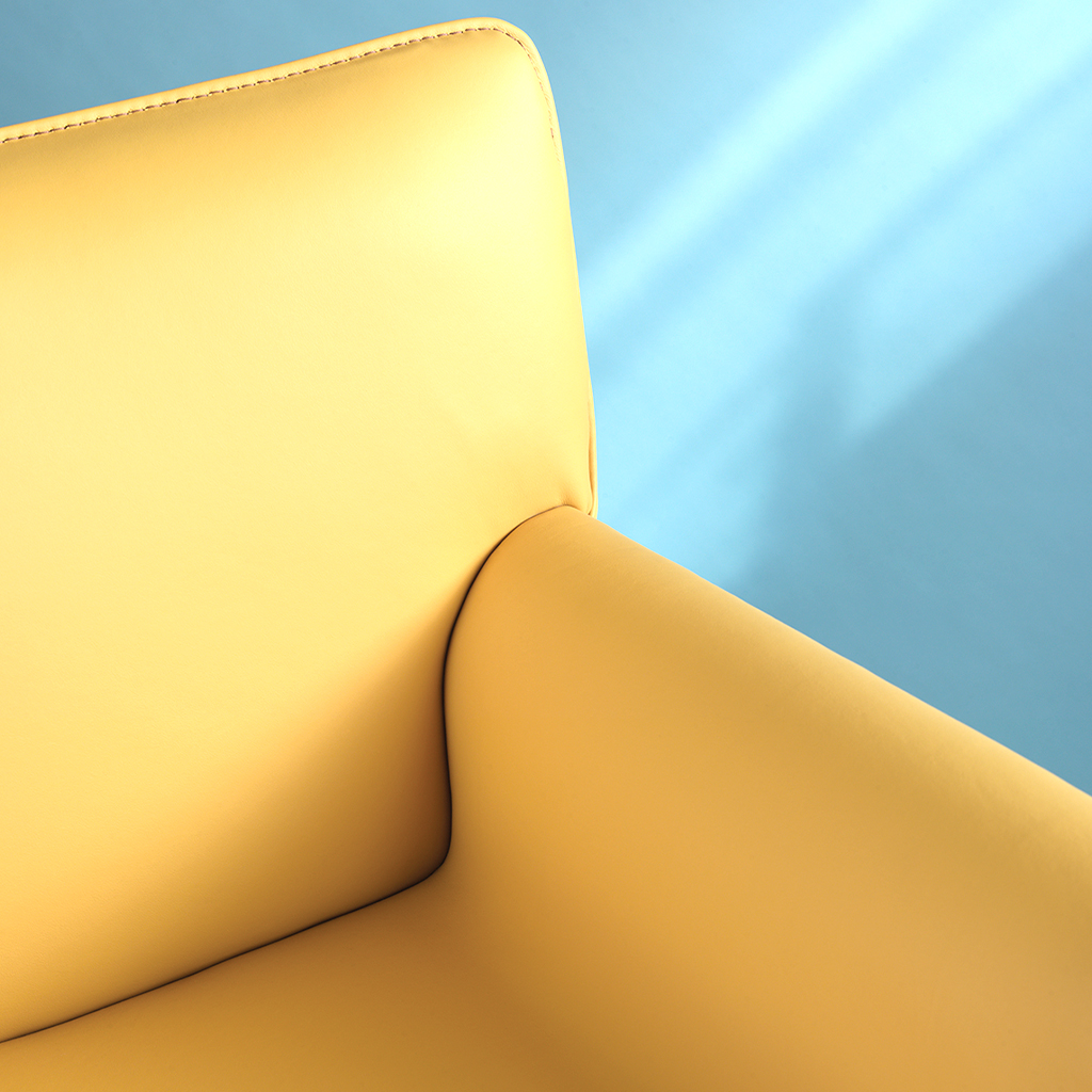 Cortina's Azzurro in the color Joy, a bright sunny yellow, is on an armchair with light coming in from the side on a blue back wall.