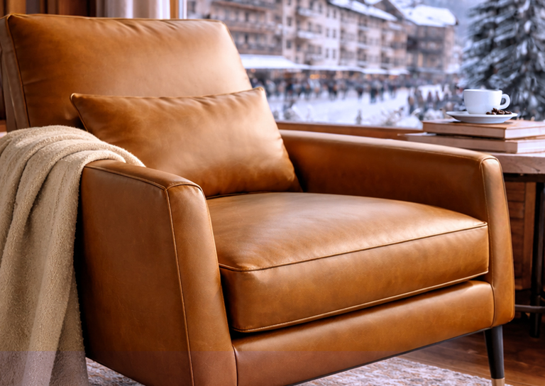 Chair wrapped in brown Cortina leather and end table with books and a cup of coffee overlooking Cortina d'Ampezzo during Winter Olympics.