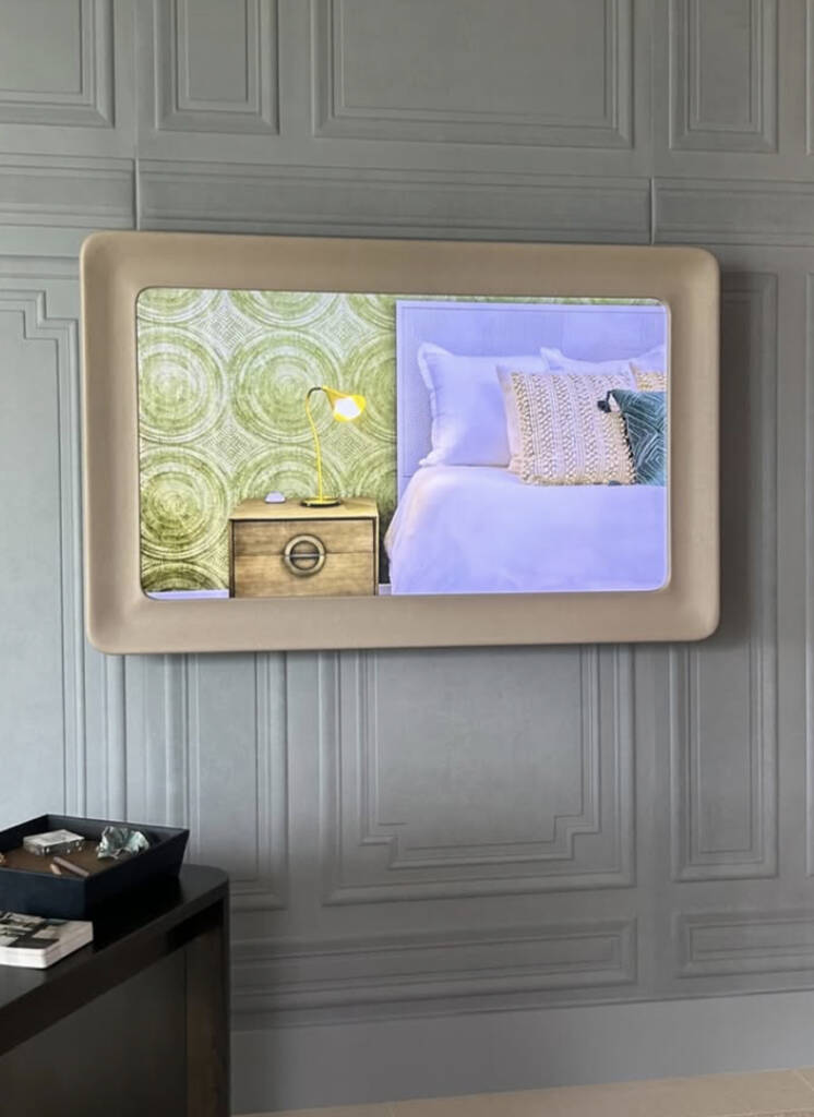 Beautiful tan Reflectel Mirror TV covered in Cortina Leathers Chaps suede in Sand over a gray paneled wall