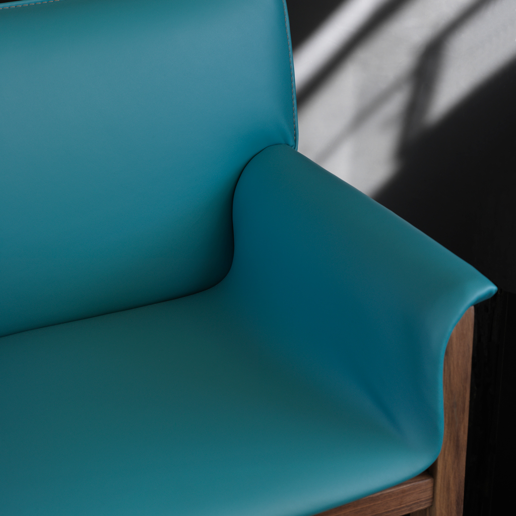 A custom made wood and leather chair shown in a deep sea blue with sun shining in on a black wall behind it